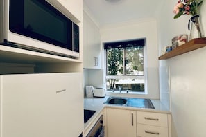 A compact kitchen with a Hisense microwave, a coffee maker, and a window with a view of trees. - Your stay the feels like home! (Lyons)