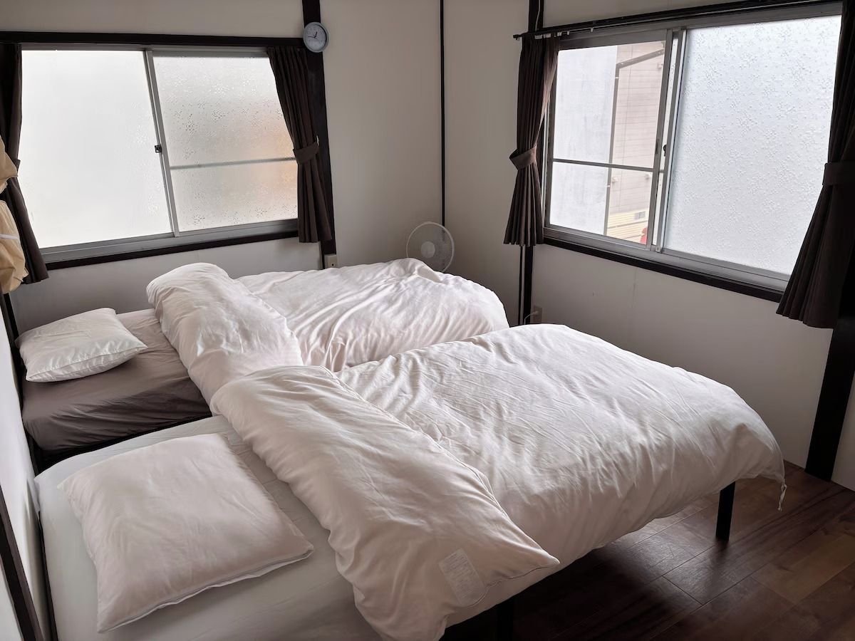 Ein Zimmer mit einem Bett, einer Uhr und einem Fenster.