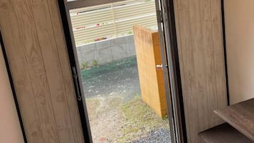 A wooden-framed door with a frosted glass panel, a green emergency exit sign, and a pendant light fixture.