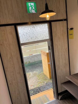 A wooden-framed door with a frosted glass panel, a green emergency exit sign, and a pendant light fixture. - New Listing (Hiroshima)