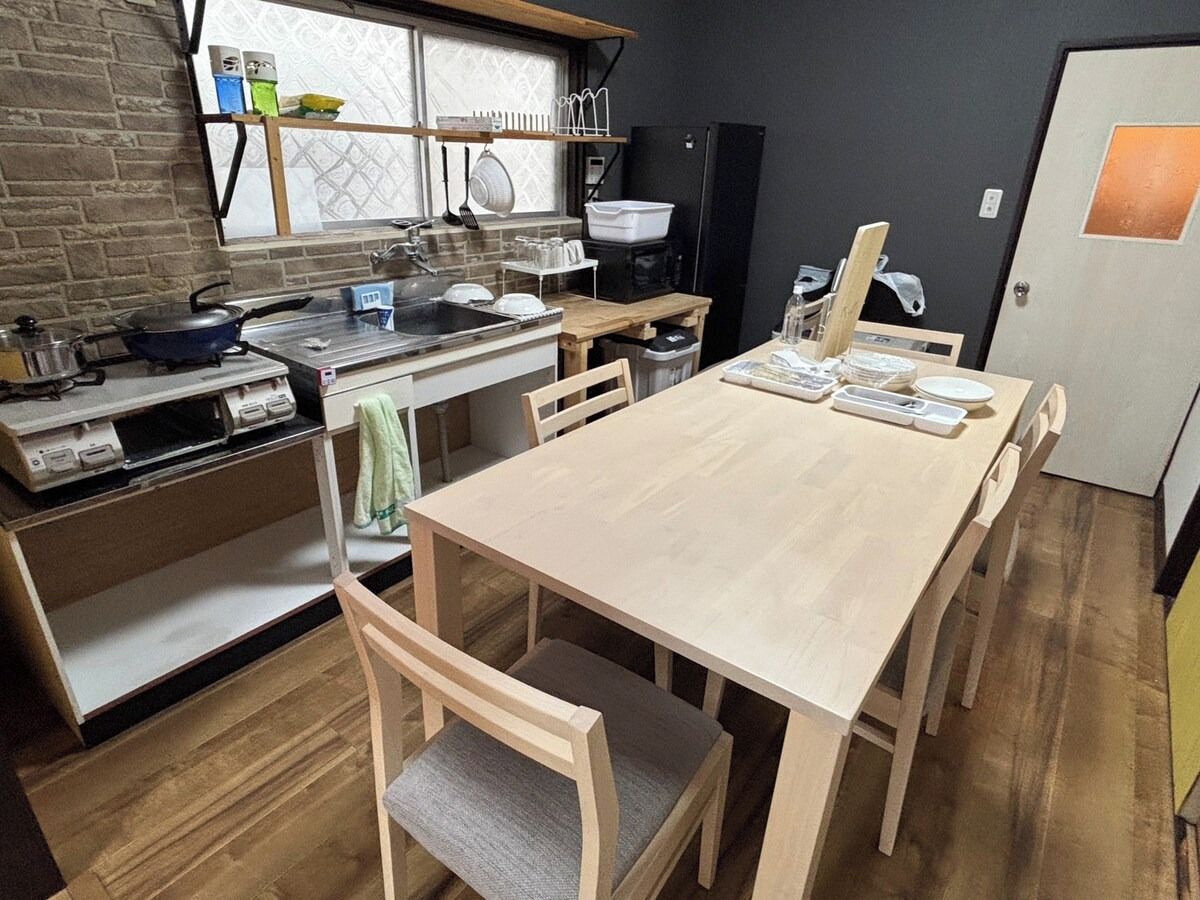 Eine kompakte Küche mit Holztisch und -stühlen, einem Herd und einem Kühlschrank.