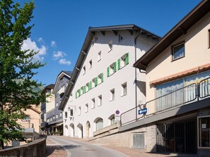 Une vue de rue montrant un immeuble doté de nombreuses fenêtres et d’un balcon avec une balustrade.