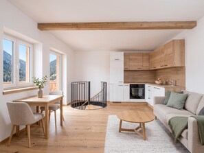 Eine moderne Küche mit Holzausstattung, ein Essbereich mit Tisch und Stühlen sowie ein Wohnzimmer mit Sofa und Couchtisch.