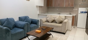 A compact living space with a sofa, a coffee table, and a kitchenette area. - AlDurra AlRaqia (Medina)