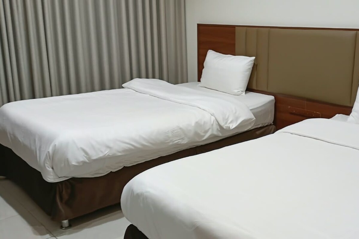 Two single beds with wooden headboards and white bedding in a hotel room.