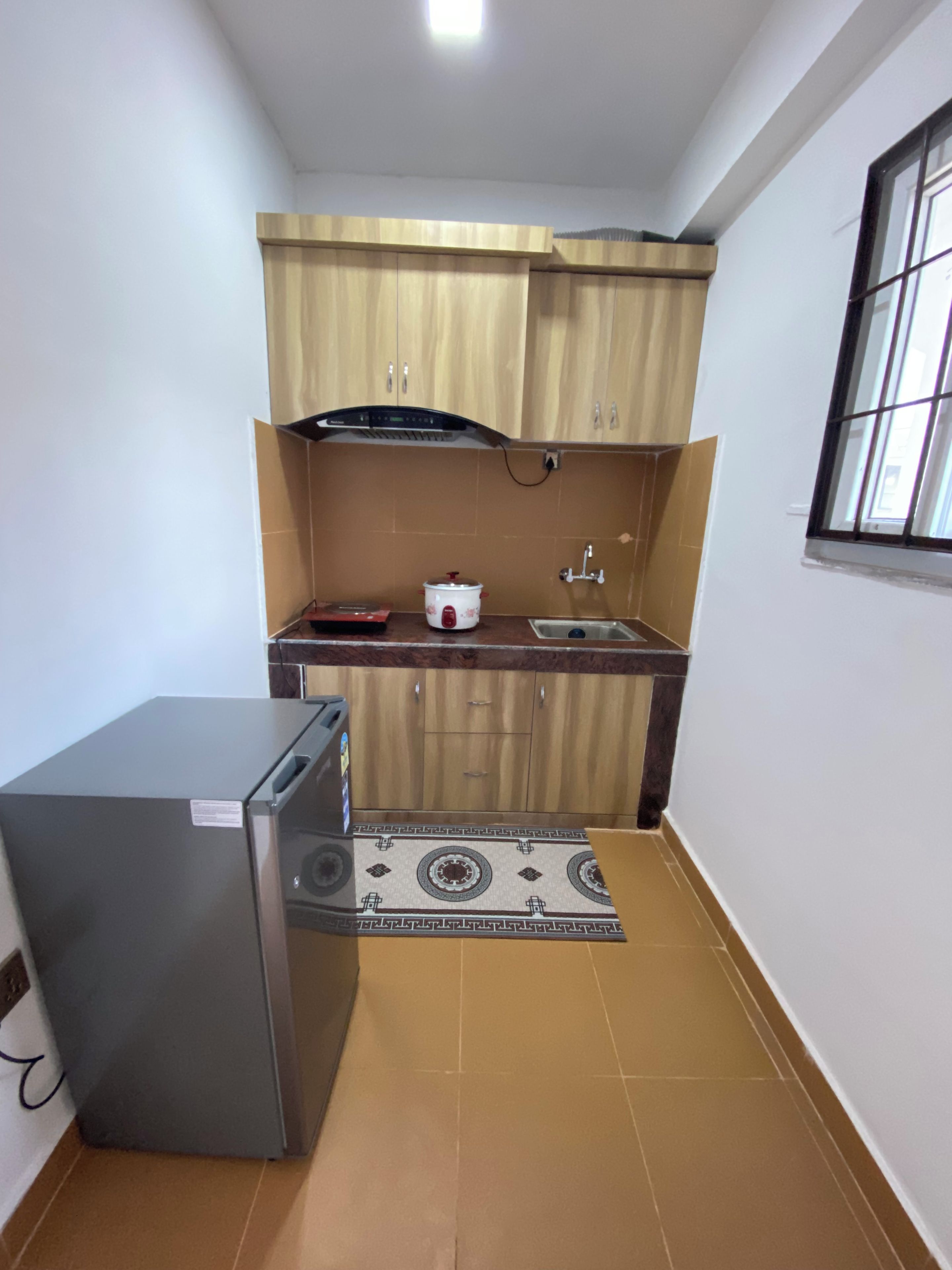A compact kitchen with wooden cabinets, a built-in stove, a sink, and a refrigerator.
