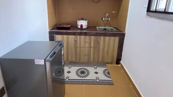 A compact kitchen with wooden cabinets, a built-in stove, a sink, and a refrigerator.