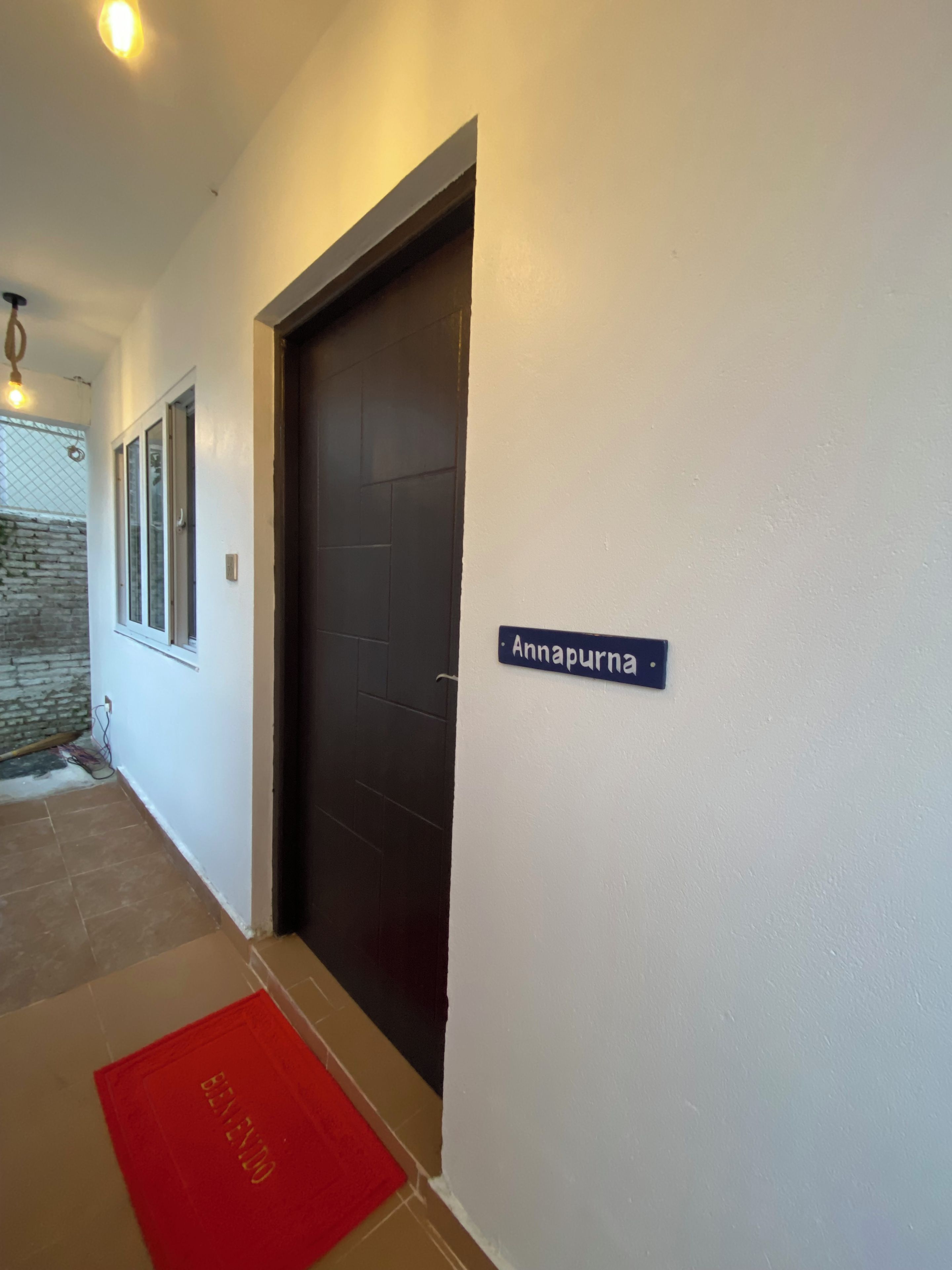 Un couloir avec une porte noire, une plaque portant le nom « Annapurna », et un tapis rouge sur le sol.