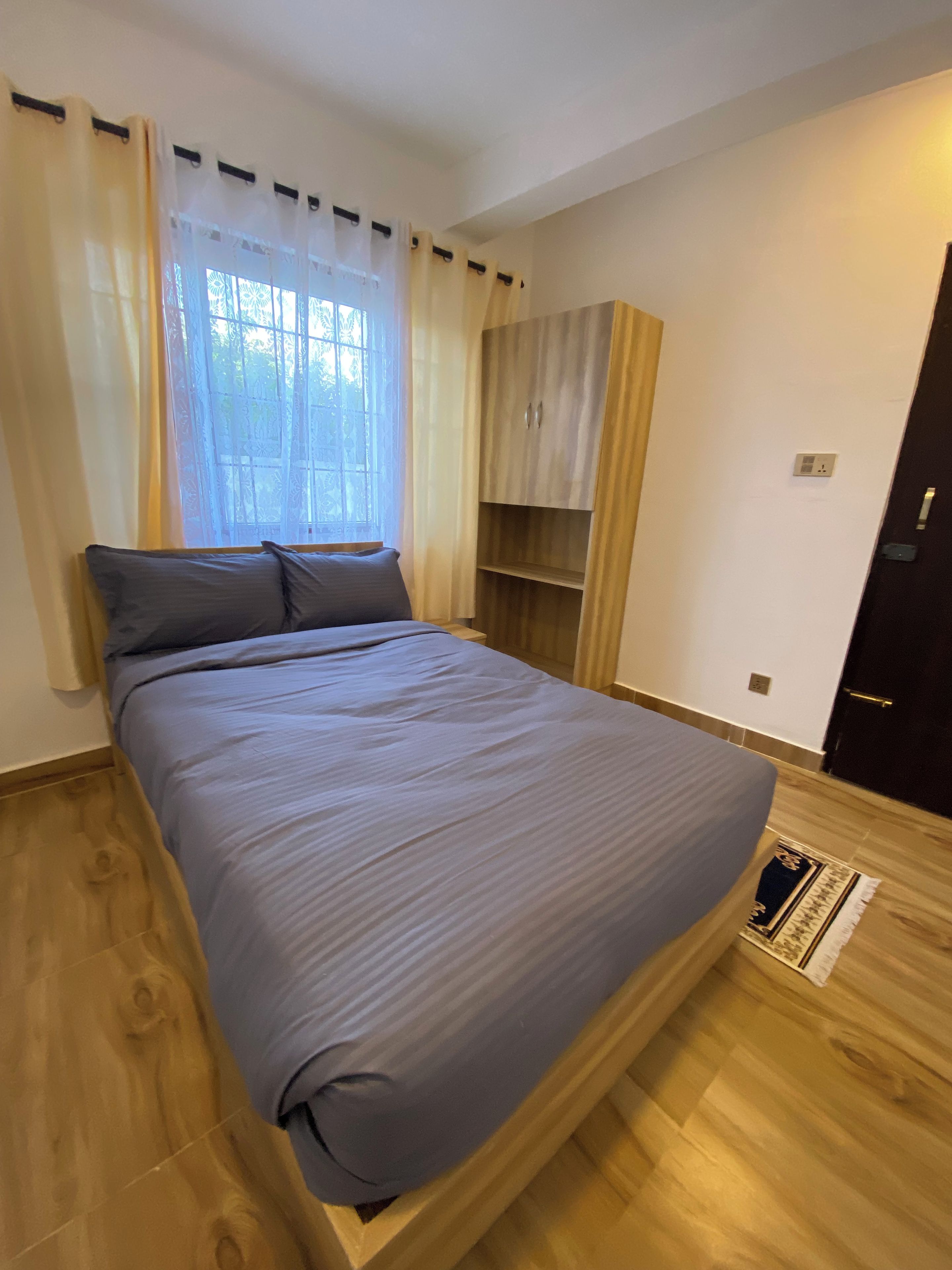 Un dormitorio con una cama, un armario y una ventana con cortinas.