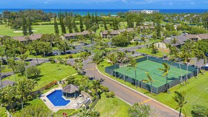 Zona residencial con cancha de tenis, piscina y campo de golf al fondo.