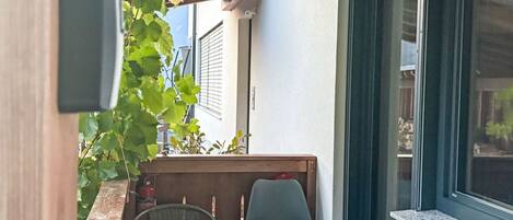A patio with a table and chairs, a hanging lantern, and a door to the building.