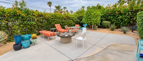 An outdoor patio area with a fire pit, lounge chairs, and planters.