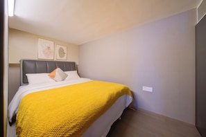 A hotel room with a bed, a headboard, a wall-mounted light, and two framed pictures. - Zhuhai Muning Hotel (Zhuhai)