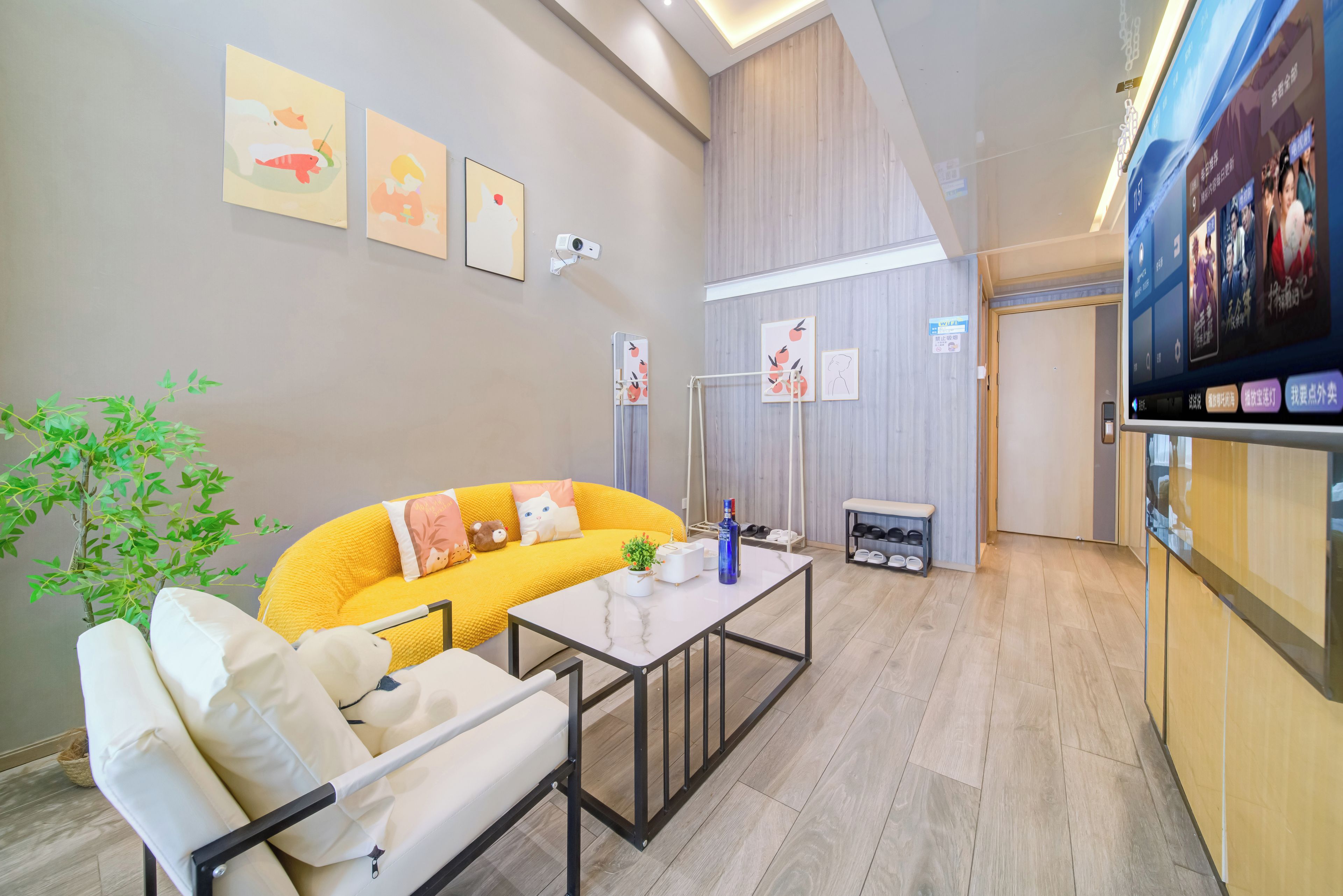 A modern living room with a yellow sofa, a white armchair, a small table, and a potted plant.