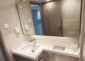 A modern bathroom with a large mirror, a sink, and a toilet. - Zhuhai Muning Hotel (Zhuhai)