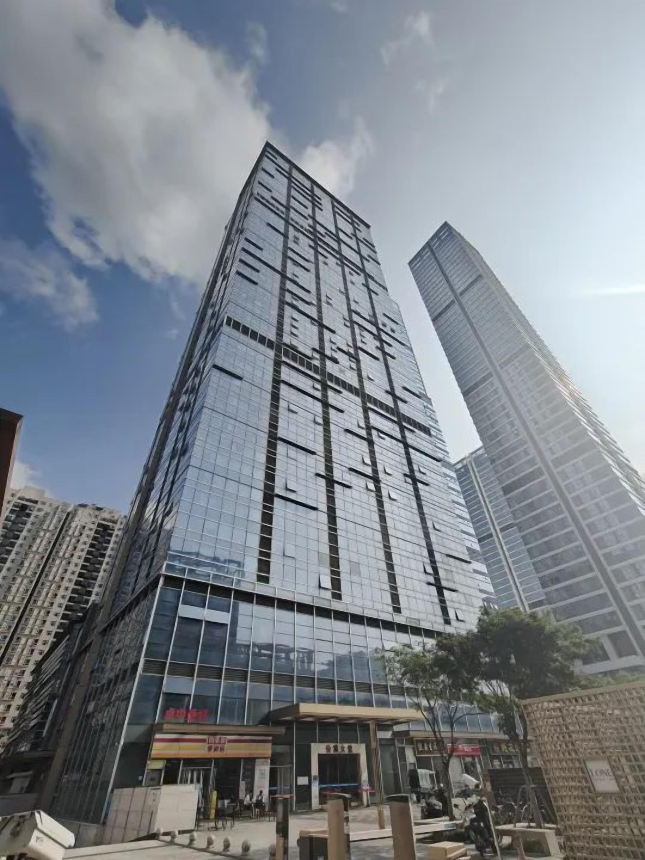 Un edificio de gran altura con fachada de vidrio, varios pisos y un nivel comercial en la planta baja con señalización.