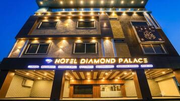 Un hotel de varios pisos con señalización iluminada, una entrada destacada y diversas comodidades, incluyendo un restaurante, salón de banquetes y salones de fiesta.