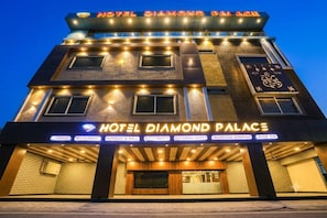 Un hotel de varios pisos con señalización iluminada, una entrada destacada y diversas comodidades, incluyendo un restaurante, salón de banquetes y salones de fiesta.
