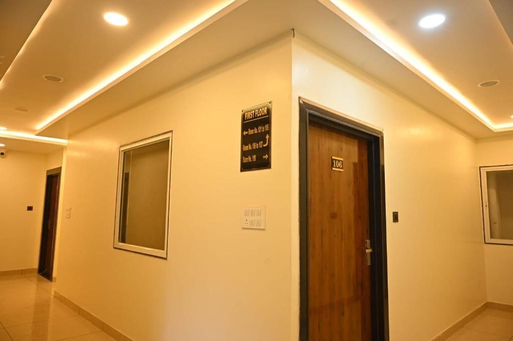 Un pasillo con un cartel que indica el primer piso, una puerta con la etiqueta '106' y un ventanal.