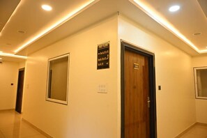 Un pasillo con un cartel que indica el primer piso, una puerta con la etiqueta '106' y un ventanal.