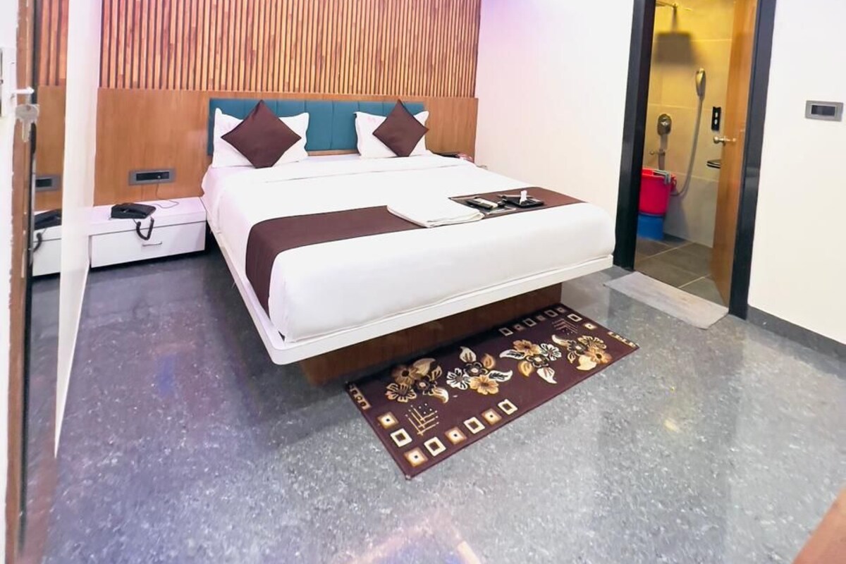 Una habitación de hotel moderna con cama, mesitas de noche, ventilador de techo y aire acondicionado.