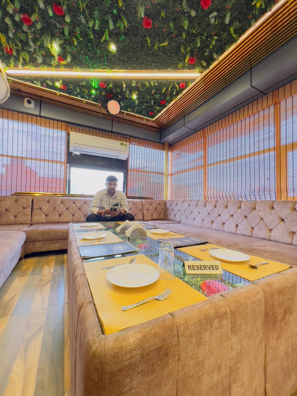 Una habitación con un conjunto de sofás, una mesa de comedor con individuales amarillos y un techo con diseño floral.