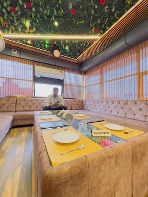 Una habitación con un conjunto de sofás, una mesa de comedor con individuales amarillos y un techo con diseño floral.