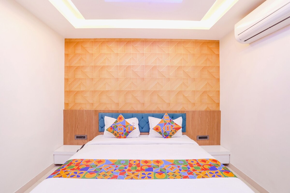 Un dormitorio moderno con un cabecero de estampado geométrico, una cama con dos almohadas y una alfombra colorida de diseño geométrico.