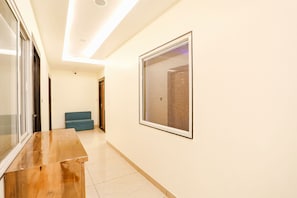 Un pasillo con un banco de madera, un cuadro en la pared y un sofá azul.