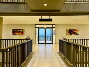 Um hall de hotel com entrada dupla central, duas grades laterais e obras de arte nas paredes.