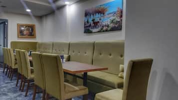 A dining area with a long table and multiple chairs, a cushioned bench, and a painting on the wall.