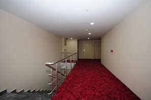 A hallway with a red carpet, a metal railing, and a door at the end. - Room-grand Hekimoğlu Hotel (Izmir)