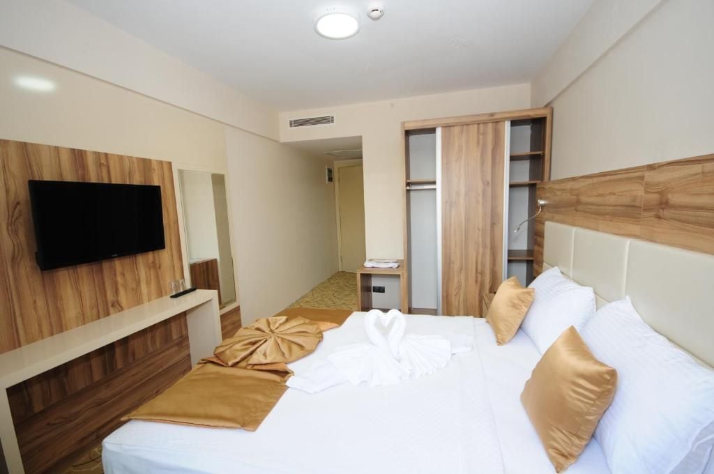 A hotel room with a bed, a television mounted on the wall, a wardrobe, and a bathroom visible through an open door.