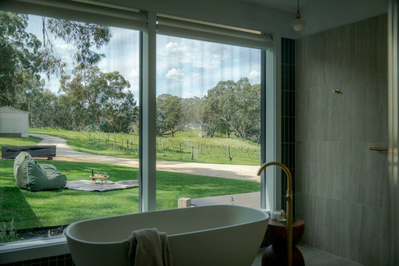 Un bagno con una vasca, una finestra vista vigneto e una panchina all'esterno.