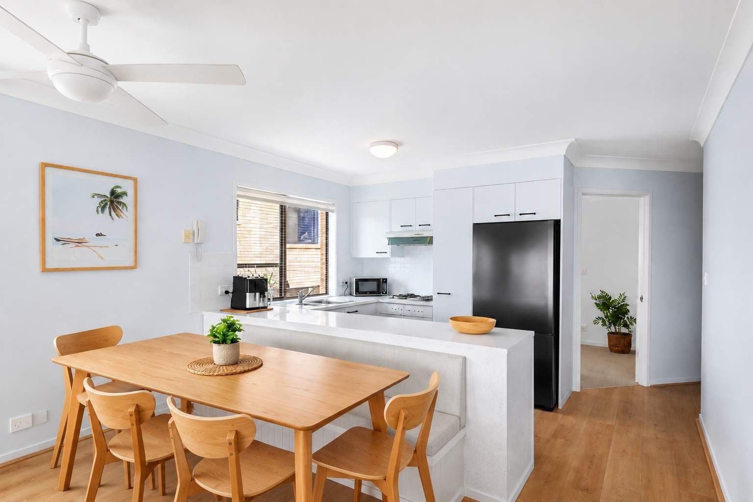 A modern kitchen with white cabinets, a black refrigerator, and a wooden dining table with chairs.