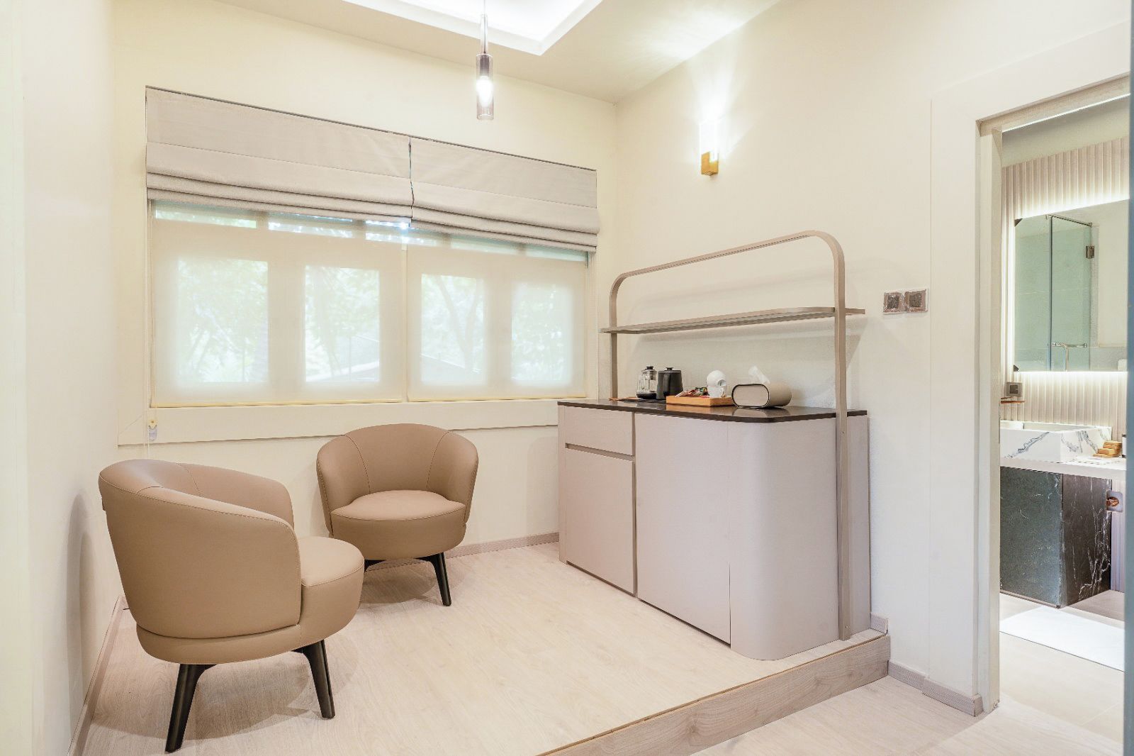 A modern bathroom with a glass shower enclosure, a vanity with a mirror, and a seating area with two chairs.