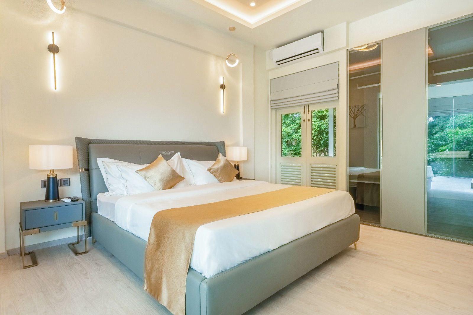 A modern hotel room with a large bed, bedside lamps, a nightstand, and a view of the outdoors through a glass door.