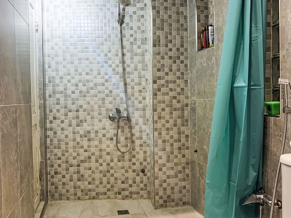 A shower area with a tiled wall, a showerhead, and a curtain. - Jbila Maison by Interhome (Tanger)