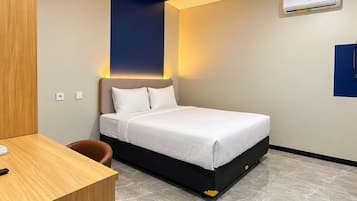 Een moderne hotelkamer met een bed, een bureau en een prullenbak.