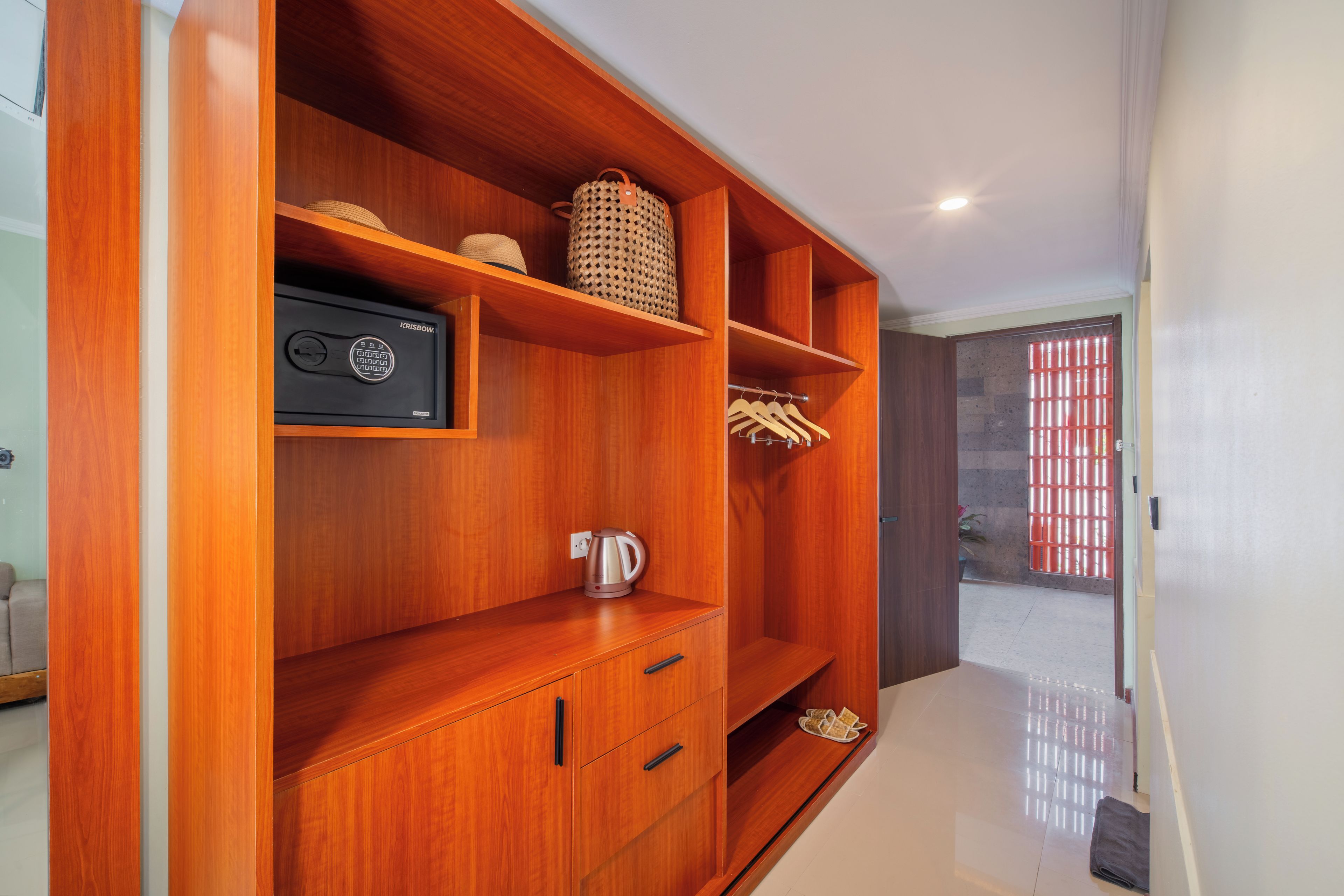 A wooden wardrobe with multiple compartments, a kettle, and a small shelf with a woven basket.