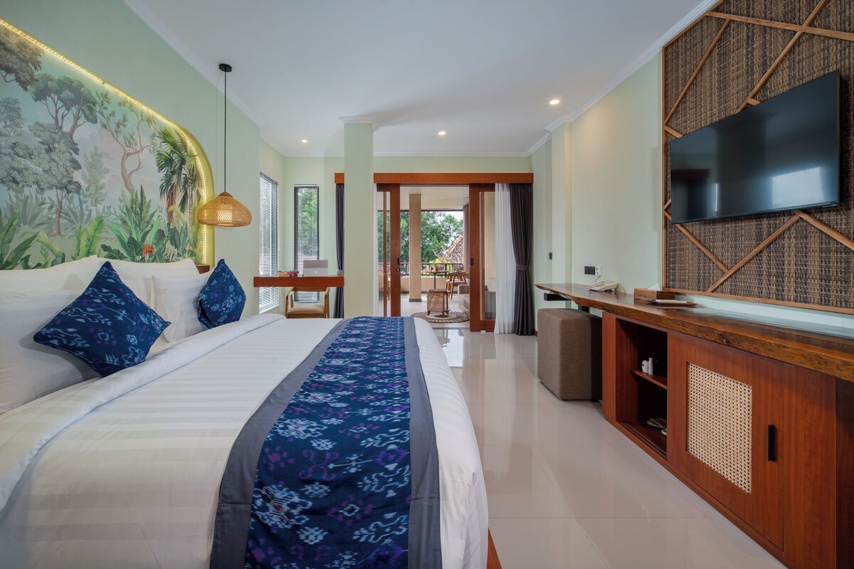 A hotel room with a bed, a desk, a TV, and a view of the outdoors.