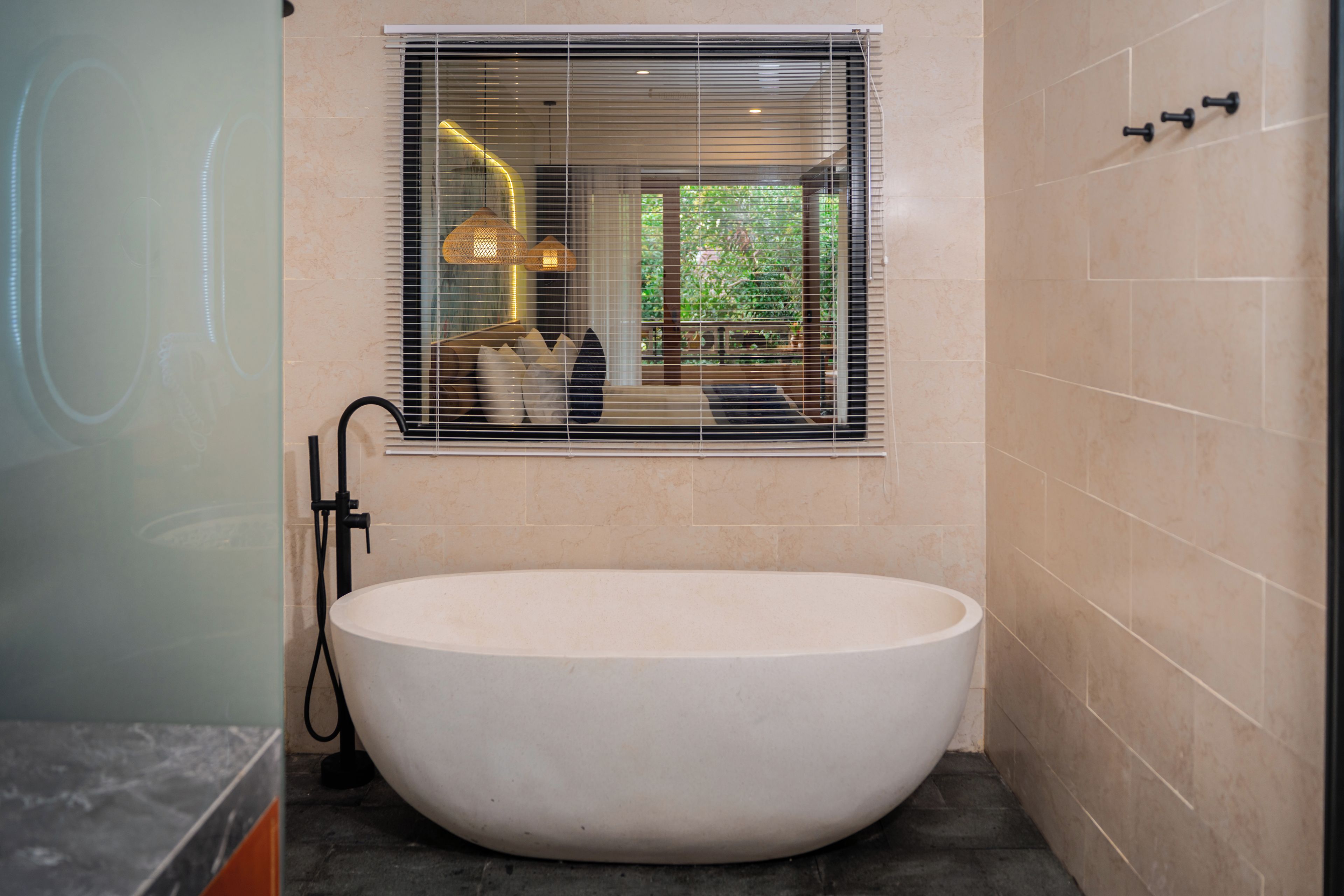 A modern bathroom with a freestanding bathtub, a window with blinds, and a towel rack.