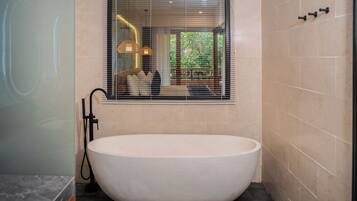A modern bathroom with a freestanding bathtub, a window with blinds, and a towel rack.