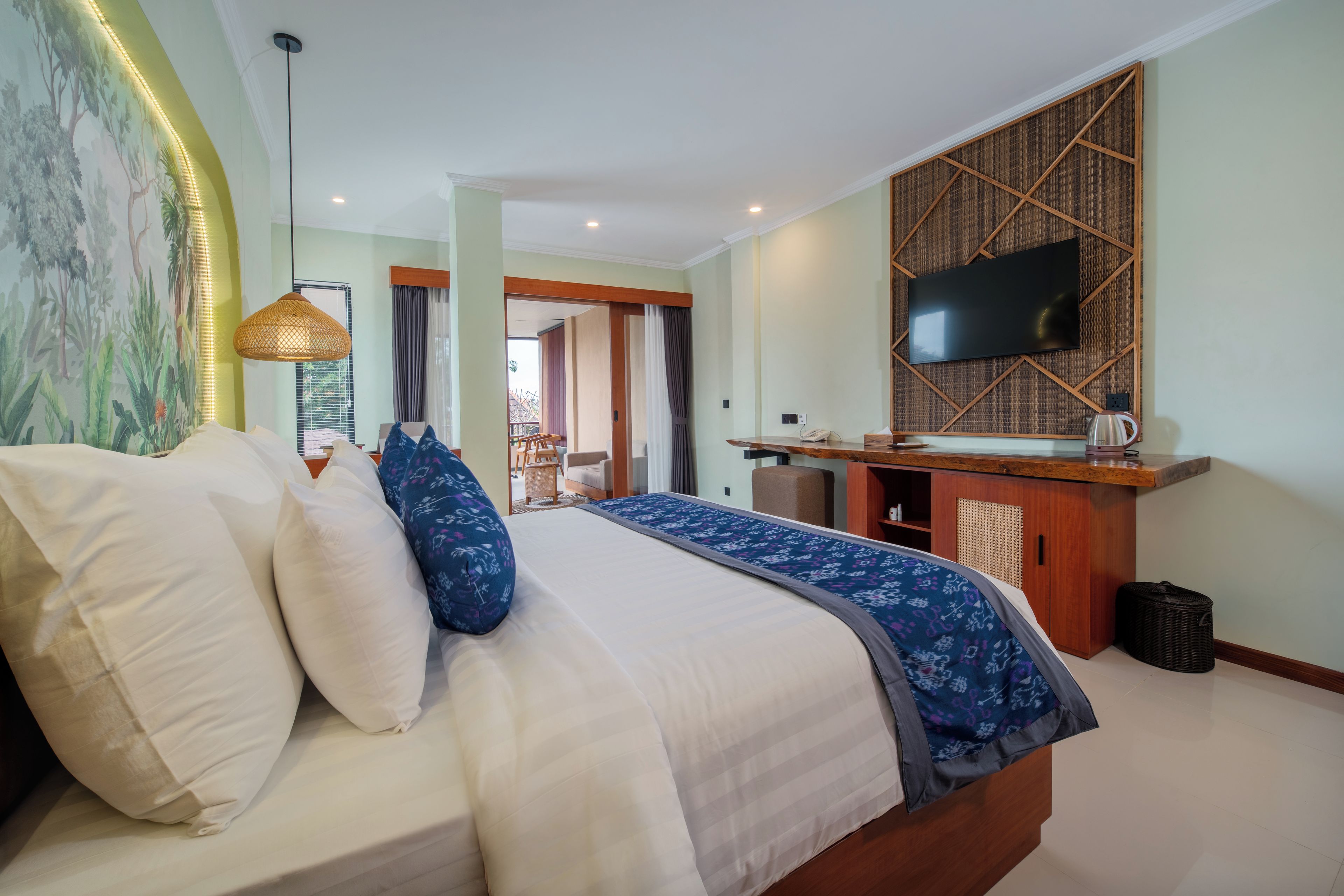 A hotel room with a bed, a desk, a television, and a view of the outdoors.