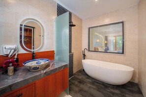A modern bathroom with a freestanding bathtub, a round mirror with a light, and a vanity with a bowl sink. - Dewangga MUA Ubud (gianyar)