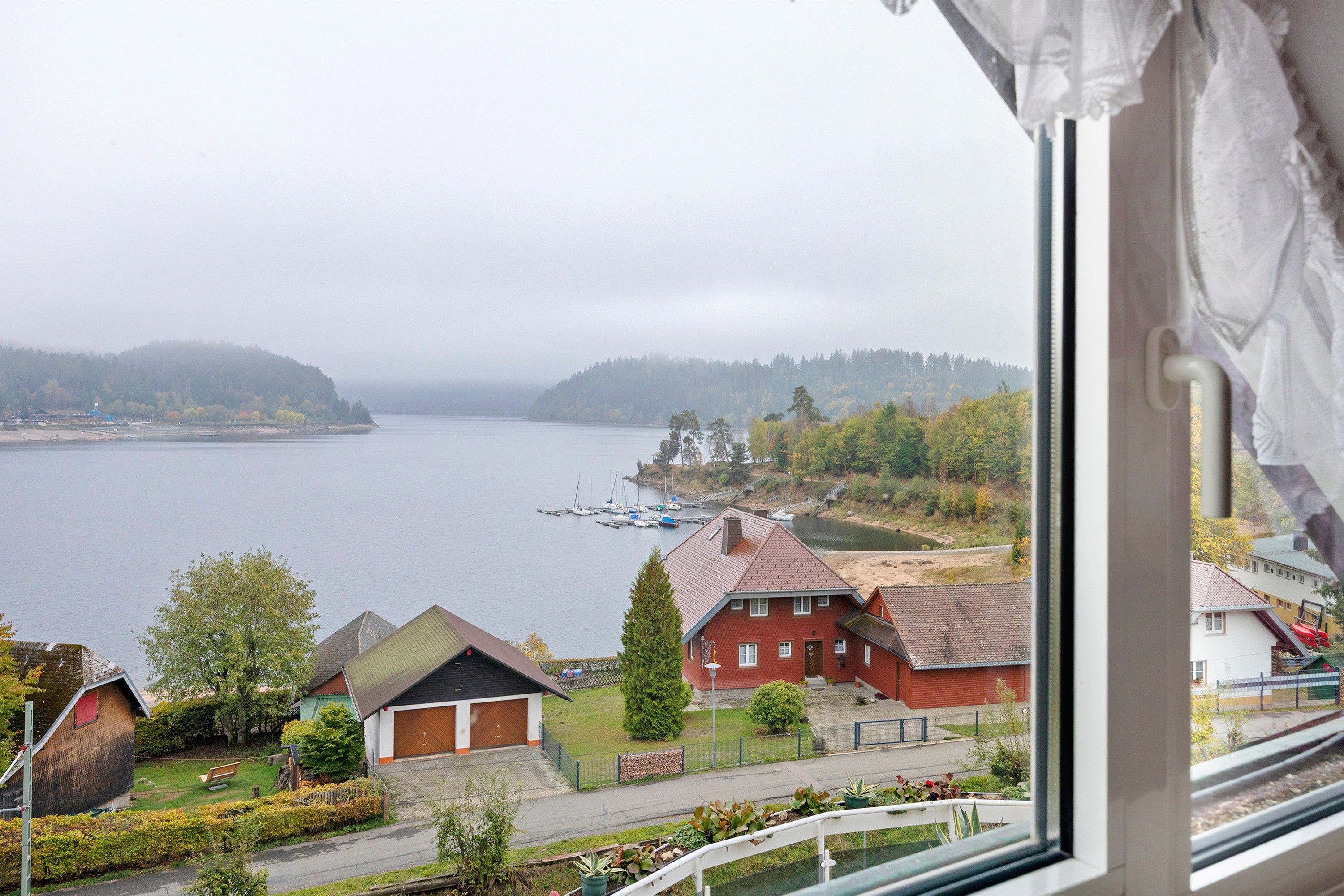 Blick auf einen See mit Booten, umgeben von Häusern und Grünflächen.