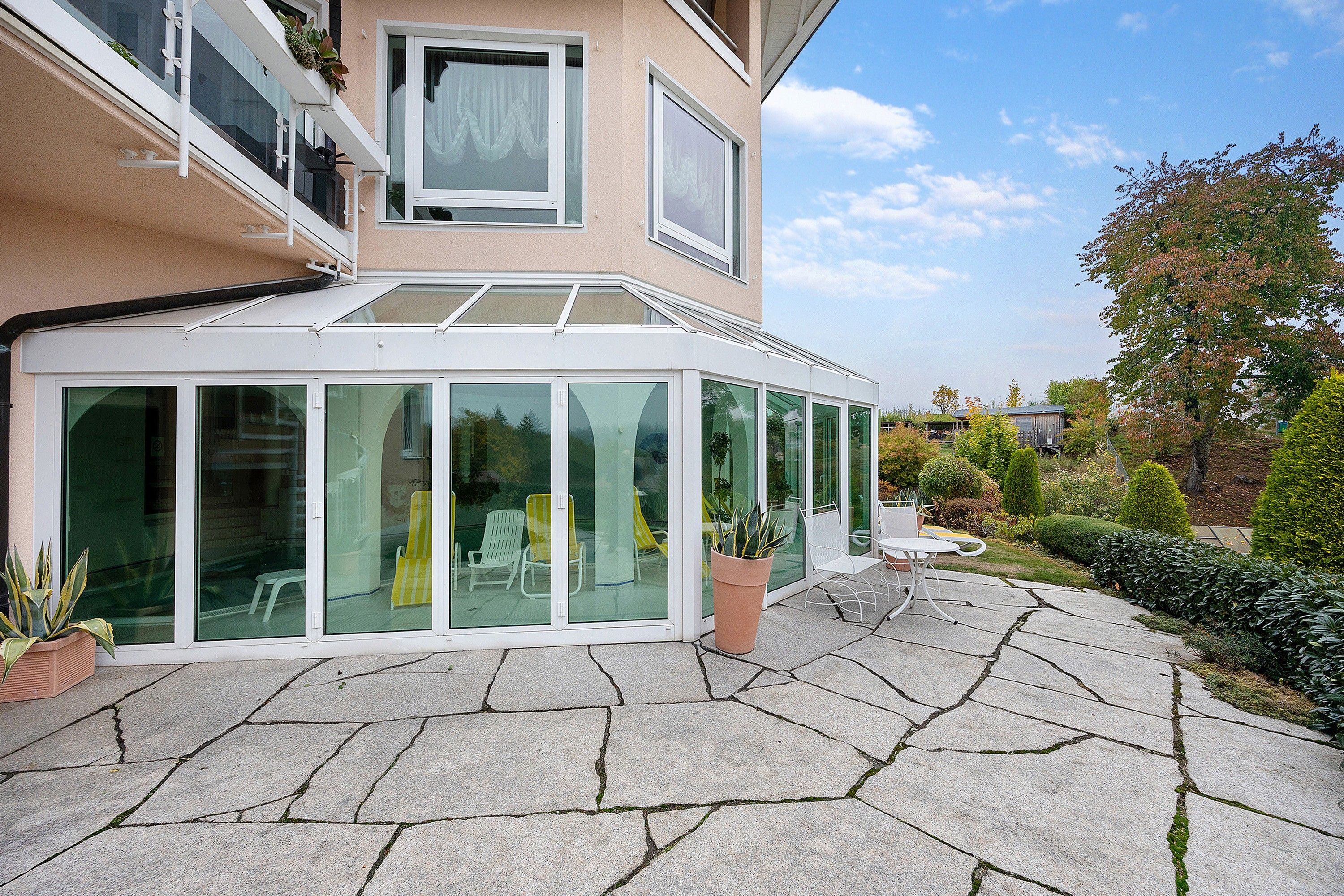 Ein modernes Haus mit Wintergarten, Steinterrasse und Garten.