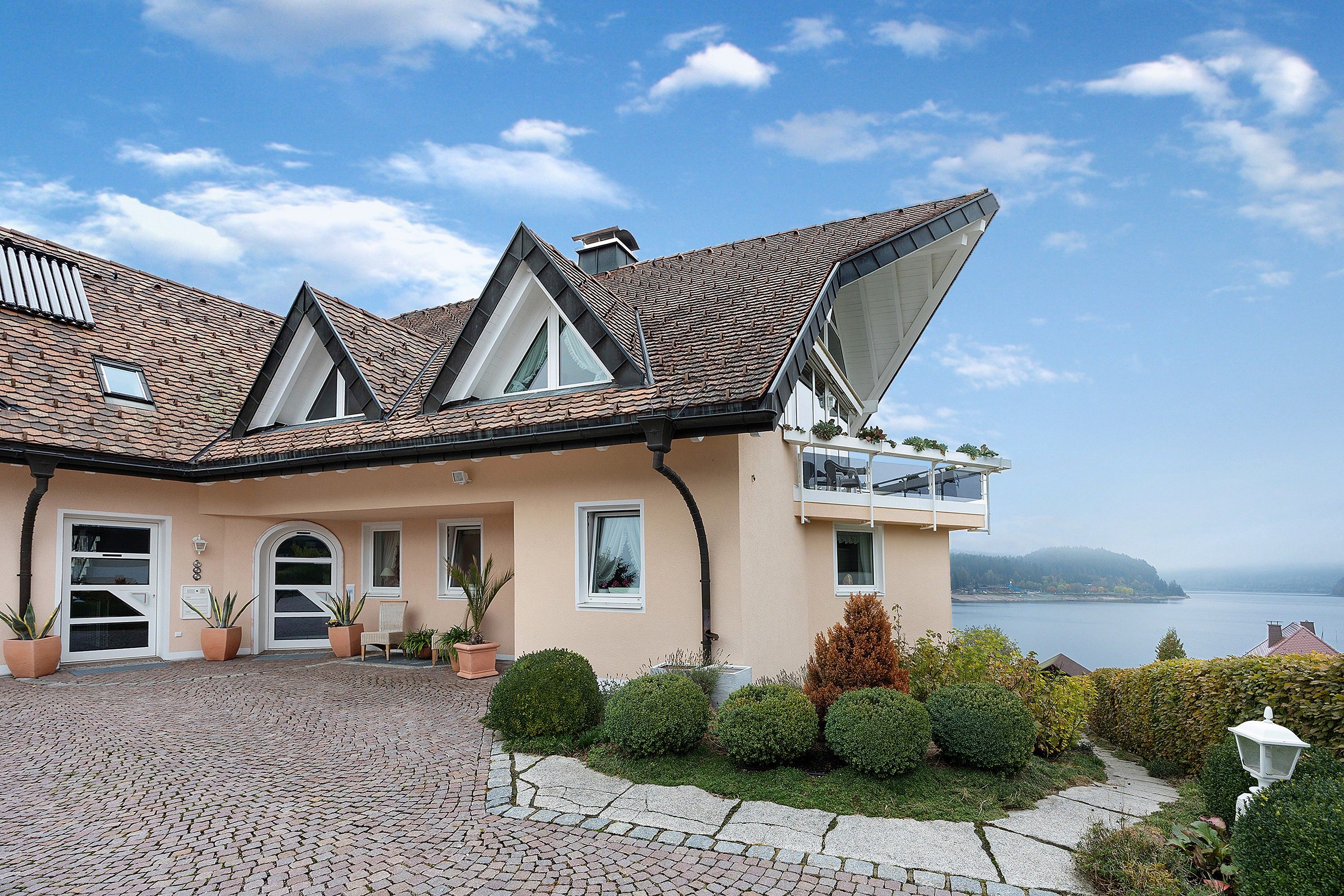 Une maison avec un toit en pente, un balcon et une vue sur la mer.