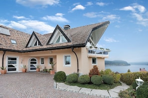 Une maison avec un toit en pente, un balcon et une vue sur la mer.