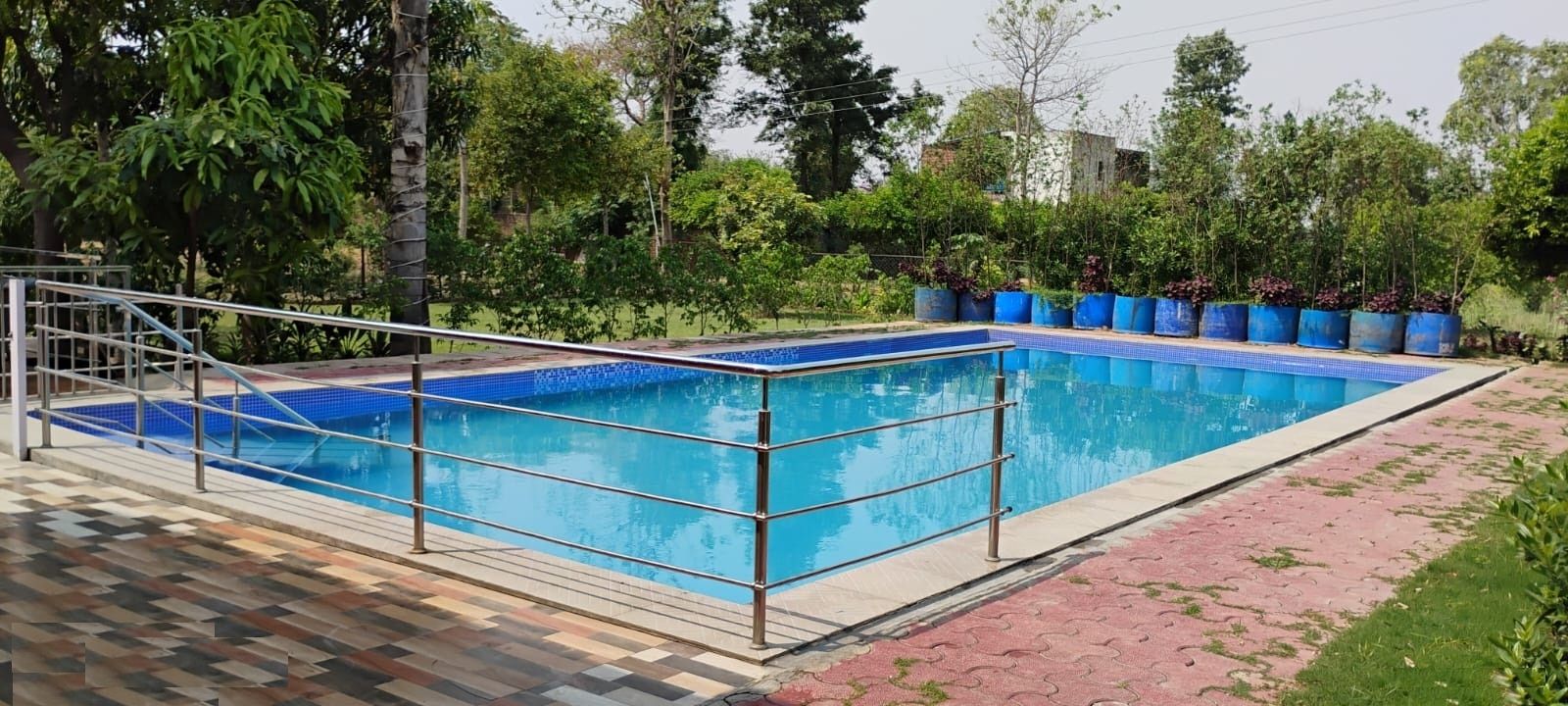 A rectangular swimming pool with a tiled edge, surrounded by a metal railing.
